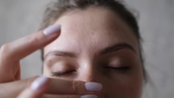 Cosmetologie procedure - het gebruik van eco serum om de huid te herstellen en te hydrateren. Close-up van een meisje dat crème op haar voorhoofd aanbrengt — Stockvideo