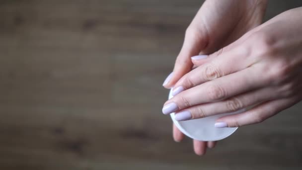 Las manos femeninas abren el paquete con parches para la cara en el fondo del suelo de madera. Cosméticos para el cuidado de la piel y la eliminación de moretones debajo de los ojos — Vídeos de Stock