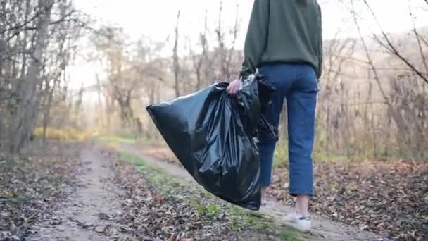 Doğanın ve çevrenin kirliliği. Kadın bacakları, büyük siyah bir çöp torbası. İnsan tarafından yapay kirlilik kavramı. — Stok video