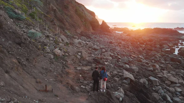 Хлопець і дівчинка стоять на березі океану на заході сонця, біля підніжжя скель, Беніхо Біч, Тенеріфе, Канарські острови, Іспанія — стокове фото