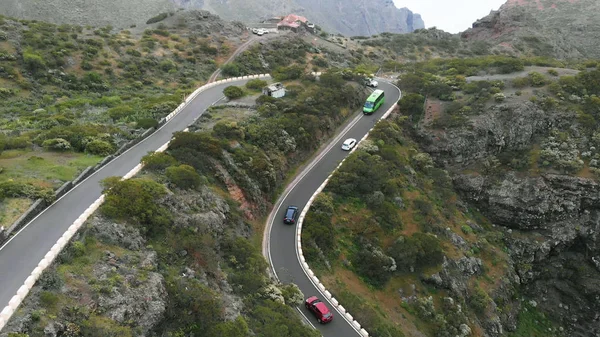 Letecký pohled. Úzký serpentin, v němž je těžké vozit automobily k sobě. Cesta podél pohoří, různá auta, tropické klima. — Stock fotografie