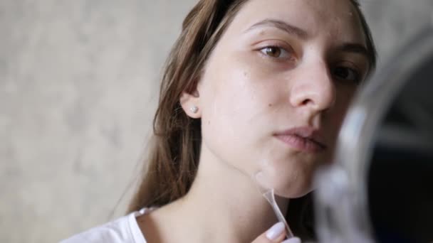 A usar creme facial. Mulher bonita está aplicando gel hidratante, sorrindo e olhando para a câmera. Close-up, tiro estático — Vídeo de Stock