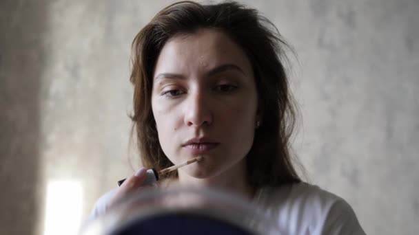 Frauenporträt beim morgendlichen Make-up. Concealer-Schmierereien auf der Gesichtshaut. Make-up Pinsel — Stockvideo