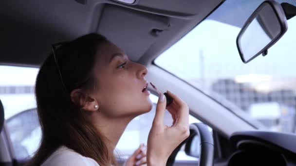 Motorista bonito feminino aplica batom para o carro. Maquiagem antes do trabalho. Bálsamo labial — Vídeo de Stock
