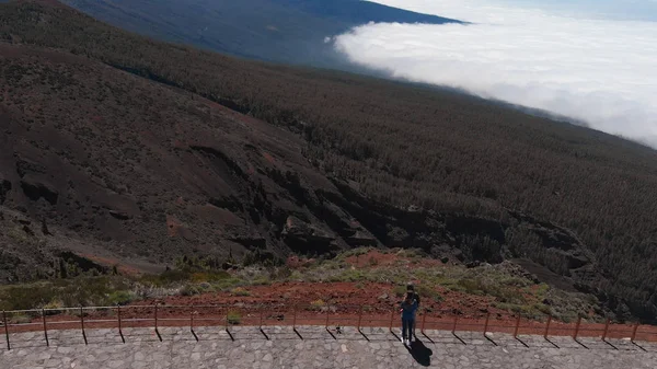 Hava görüntüsü - genç bir çift gözlem güvertesinin kenarında duruyor. Teide volkanı manzarası ve sık orman ve bulutlarla kaplı vadi. Mars manzarası. — Stok fotoğraf