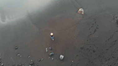 Kız güzel siyah bir plajda okyanusa gider. Tepeden tırnağa bak. Kanarya Adaları, volkanik kum, çekici bir model.