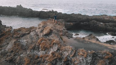 Volkanik bir kayanın kenarında duran bir adamın üzerinde vızıldamak. Tenerife, İspanya