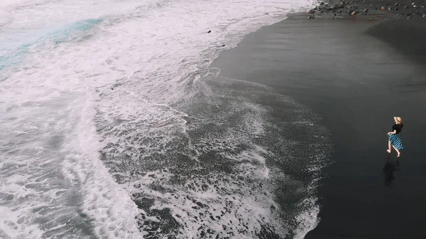 Foto aerea di una bella ragazza in una gonna lunga e cappello sulla costa atlantica. Sabbia nera, bel mare, donna attraente — Foto Stock