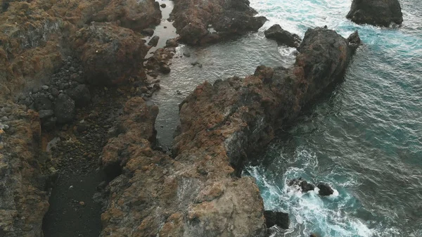 Vue aérienne des roches de lave gelées, sur la côte de l'océan. Une plage d'origine volcanique, rochers dans l'eau à côté des piscines naturelles de Tenerife, Espagne, un lieu secret. Oiseaux vue d'oeil . — Photo