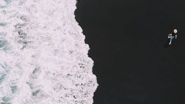 La migliore vista aerea di Tenerife. Donna elegantemente vestita correre lungo la spiaggia sulla sabbia nera, dietro le sue tracce. Vista dall'alto sulla spiaggia di Socorro. Isole Canarie, Spagna — Foto Stock