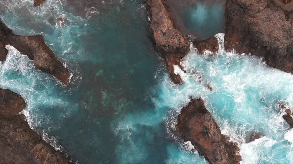 Cinematic shot - drone boven de kust van de Atlantische Oceaan, Tenerife, Spanje. Rots in kristalhelder water gewassen door oceaanschuim — Stockfoto