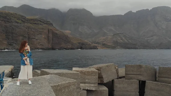 Uitzicht vanuit de lucht - een prachtig meisje tegen de achtergrond van grote mistige bergen en donkere Atlantische Oceaan op een bewolkte dag. Agaete, Gran Canaria, Spanje — Stockfoto