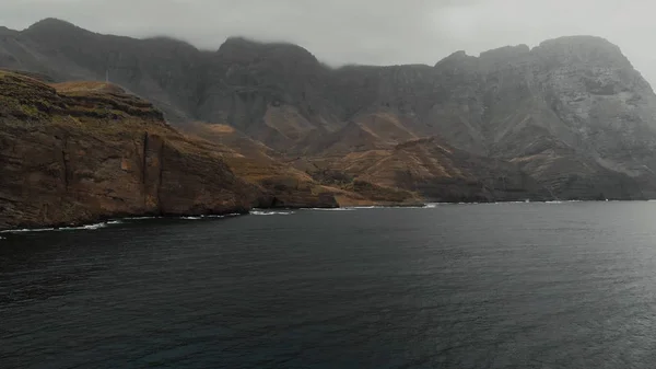 Güzel sinematik aero çekim - büyük sisli dağlar ve karanlık ve derin Atlantik Okyanusu, insanlar olmadan. İnsansız hava aracından manzara, panoramik manzara. Parque Doğal Tamadaba, Agaete, Gran Canaria.