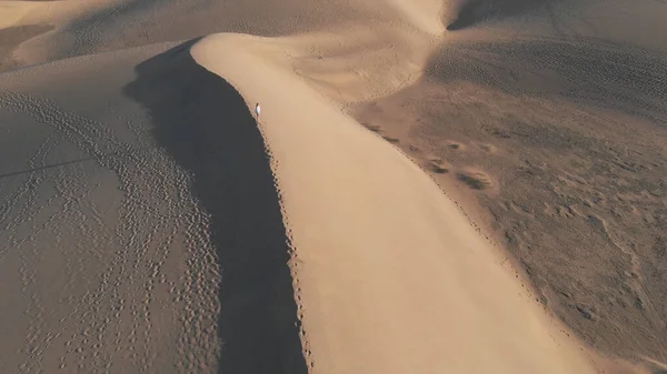Вид с воздуха - красивая девушка, стоящая на дюне на закате или восходе солнца. Над пустыней - панорама главной достопримечательности острова Гран-Канария - Маспаломас — стоковое фото