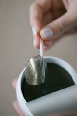 Kozmetik ameliyatına hazırlanırken kız paketten bir göz bandı çıkarıyor. Gözlerinin altındaki deriyi kaldırır, nemlendirir ve sıkılaştırır.