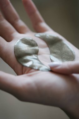 Bir kadının kolundaki göz bantları yakın plan. Yin yang şeklinde kozmetik ürünler.
