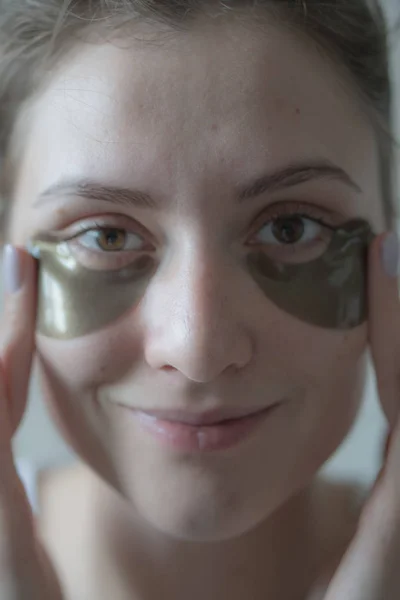 Hidratar e apertar a pele sob os olhos com a ajuda de cosméticos coreanos - belos adesivos para remover o inchaço. Procedimento de elevação, linda menina caucasiana — Fotografia de Stock