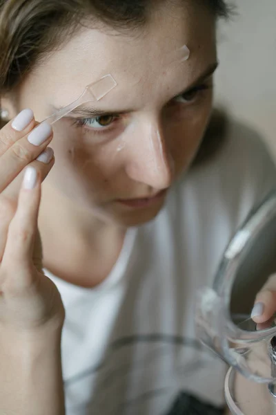 Usando crema facial. Hermosa mujer está aplicando gel hidratante. Retrato de primer plano —  Fotos de Stock