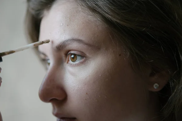 A mulher põe um tom bege na pele. Preparação, aplicação de maquiagem. Retrato de close-up — Fotografia de Stock