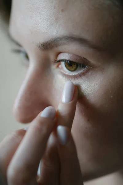 Uma mulher bonita alinha o corretor debaixo do olho. Correção da pele com cosméticos naturais — Fotografia de Stock