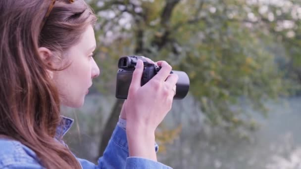 En ung kvinnlig fotograf i naturen, skjuter vilt på hösten i skogen. Fotografering av hobby eller yrke — Stockvideo
