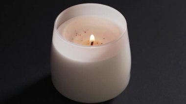 Isolated beautiful white candle in the glass burns on a black background, in the center. The Flame of Hope, Faith and The Church