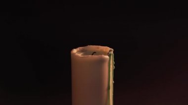 A mans hand sets fire to a candle on a black background with a match. Isolate, static shot. The concept of witchcraft, divination and magic