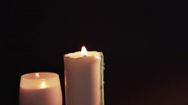 A woman tries and extinguishes a candle on a black background. 2 burning candles, isolate. Romantic evening, the end of the holiday