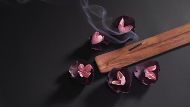 Bastone religioso aromatico su sfondo nero in uno stand di legno. Fiori secchi profumati e lenitivi nella spa. Il concetto di zen e meditazione — Video Stock