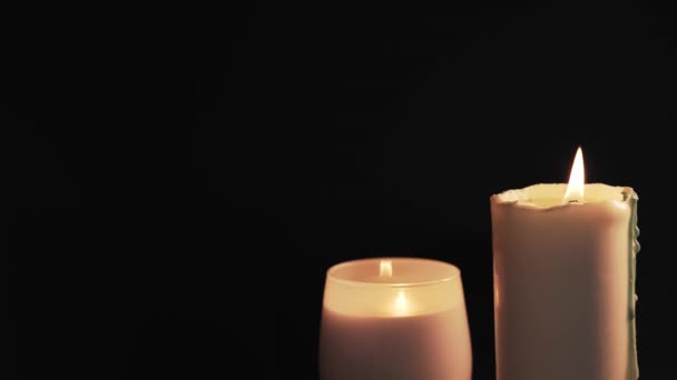 Two white burning candles are isolated on a black background. The concept of hope and faith — Stockvideo