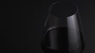 Red wine flows into a fragile glass on a black background. Sommelier fills a sweet alcoholic beverage glass in a bar close-up, isolated