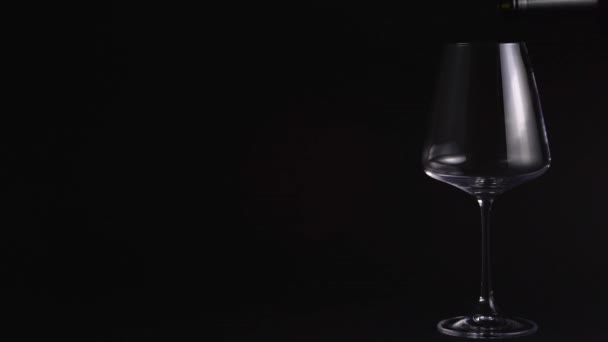 Сомельє вливає червоне вино в красиву порожню склянку. Дегустація вина в барі або ресторані. Ізольований, чорний фон — стокове відео