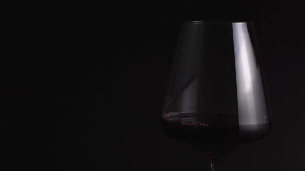 Versare il vino rosso in un bicchiere in primo piano. Bevanda costosa per festeggiare in un ristorante. Isolato, sfondo nero, illuminazione professionale — Video Stock