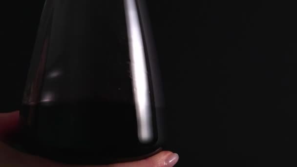 The expert rotates a glass of red wine for tasting. Expensive old alcohol, traditional check. Isolated, black background — Stockvideo