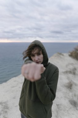 Kadın kickboksör eğitimi ve açık havada boks. Eşofmanlı genç kendine güvenen sporcu kadın hava saldırısı düzenliyor.