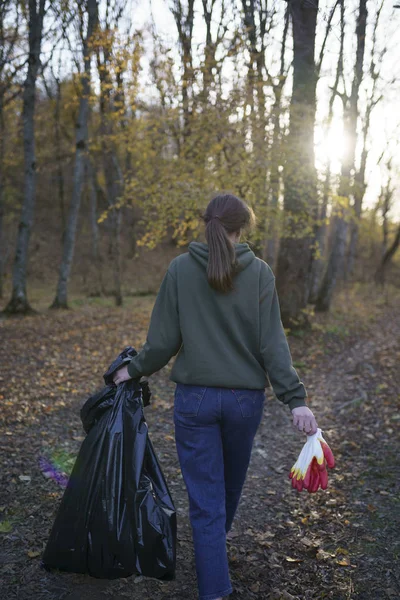 Pollution of nature and the environment. Woman with big black trash bag. The concept of artificial pollution of nature by people