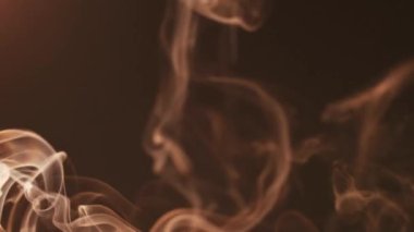 Cinematic light smoke on a dark background moves in different directions and forms beautiful figures. The concept of aromatherapy and smoking
