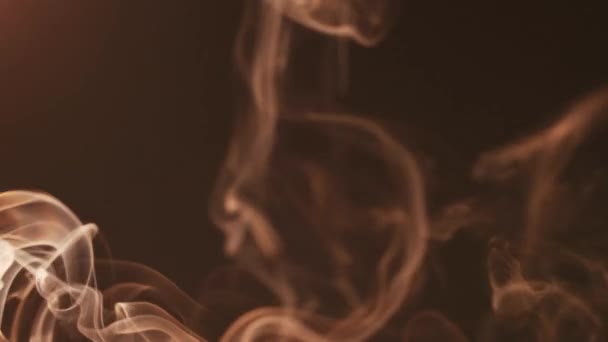 El humo luminoso cinematográfico sobre un fondo oscuro se mueve en diferentes direcciones y forma hermosas figuras. El concepto de aromaterapia y fumar — Vídeo de stock