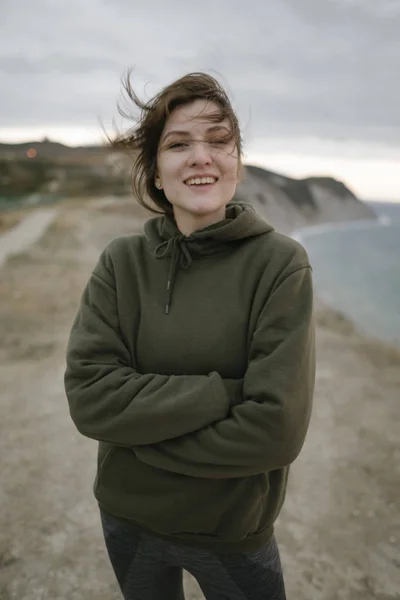 Mooie sportvrouw in een orkaan wind buiten. Portret van een slanke vrouw in sportkleding en een sweater. Het concept van fitness, succes en gezonde levensstijl — Stockfoto