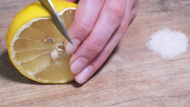 Female hand cuts into slices fresh lemon on a wooden table. Salt for tequila in the background. Guacamole recipe close-up — Stock Video