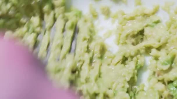 Guacamole recipe, third step. Careful stirring of the crushed avocado in a white plate, a static macro shot. Healthy Mexican traditional food from natural products — ストック動画