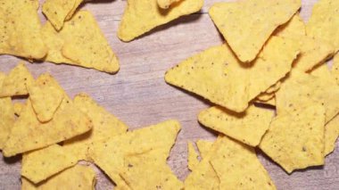 Stop motion of nachos chips on a wooden background, copyspace for your text. Mexican snack close-up, harmful and caloric food