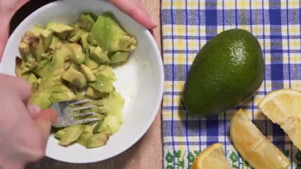 Cooking guacamole from raw avocado, stop motion timelapse, view from above. Vegetarian snack recipe made from natural products — Stock videók