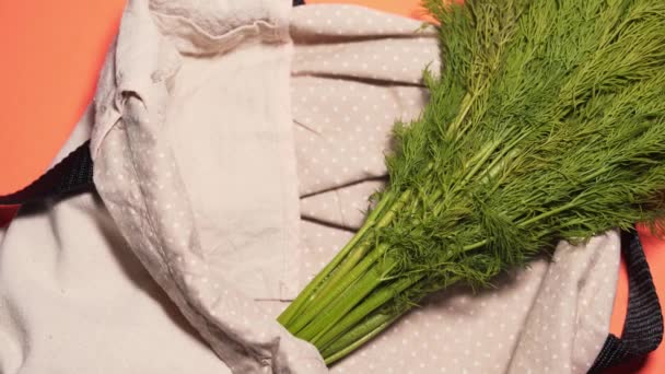 Eine wiederverwendbare Öko-Einkaufstasche auf einem Pfirsichhintergrund, isoliert. Hände legen frisches Gemüse in den Korb im Laden — Stockvideo