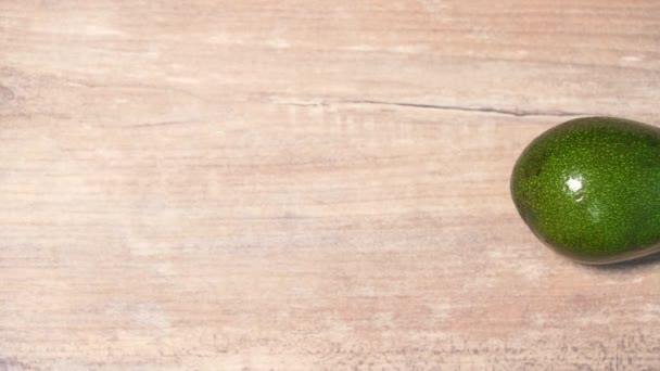 The beautiful green avocados move behind each other on a wooden background. Healthy vegan diet, healthy breakfast — Stock video