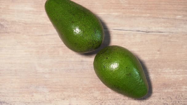 Detener el movimiento del aguacate en forma de reloj en una encimera de madera, una vista desde arriba — Vídeo de stock