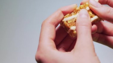 Breaking a healthy snack close-up. Energy bar granola in hand