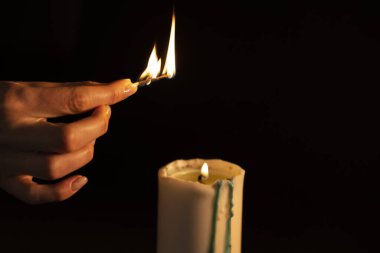 Aromaterapi kavramı - bir kadının eli, siyah arka planda izole edilmiş beyaz bir mumu ateşe verir. Spa 'da rahatlama ve meditasyon