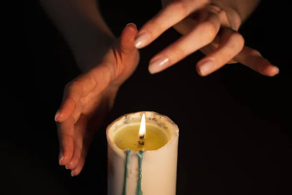 Mysterious magic close-up - womens hands conjure over a burning candle in isolation on a black background. The concept of prediction, clairvoyance and divination — Stock Photo, Image