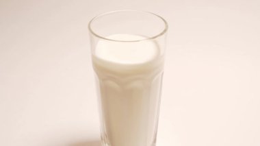 Stop motion pouring in a glass of fresh vegetarian yogurt on coconut milk. Eco milk in a transparent glass on a white background, isolated